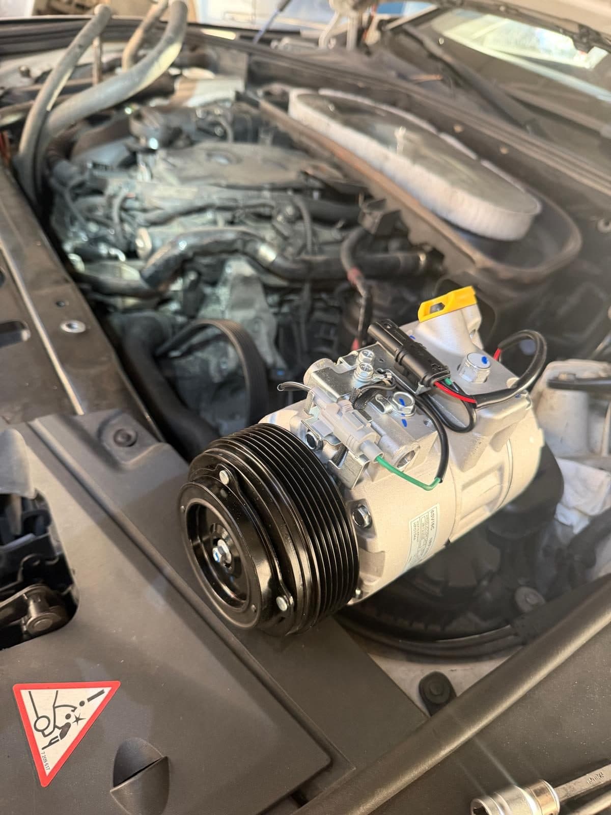 Compresor de aer conditionat auto in timpul unei interventii de incarcare freon